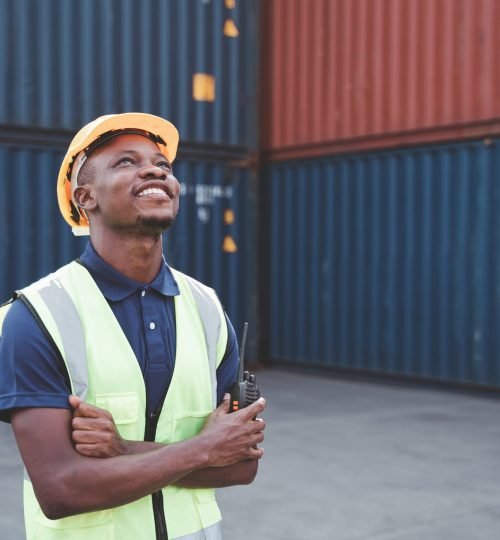 Happy African worker smailing, standing in the container workplace and crossed arms with feeling happiness